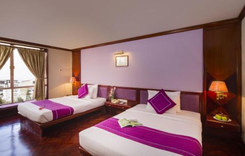 a hotel room with two beds and a window at TTC Hotel - Da Lat in Da Lat