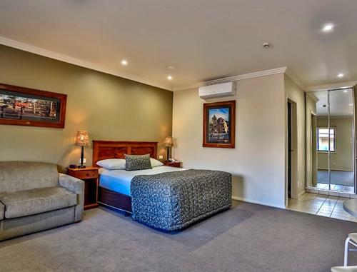 a bedroom with a bed and a couch and a chair at The Saltbush Motor Inn in Hay