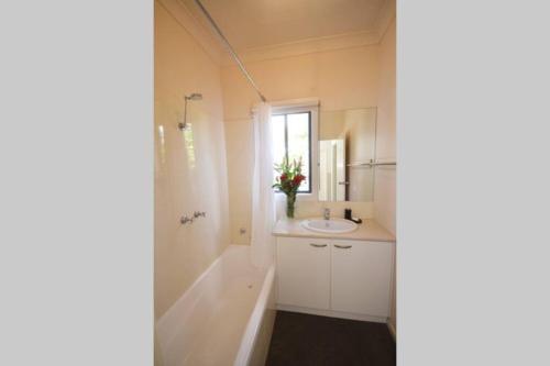 uma casa de banho branca com um lavatório e um espelho em No.40 Echuca - Echuca Holiday Homes em Echuca