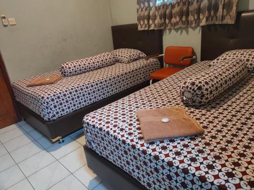 a hotel room with two beds and a chair at Homestay Wijaya Mulya in Magelang