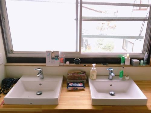 two white sinks in a bathroom with a window at yado & kissa UGO HUB in Yuzawa