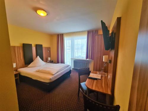 ニュルンベルクにあるホテル シルバーホーンのベッドとデスクが備わるホテルルームです。