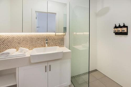 een witte badkamer met een wastafel en een spiegel bij Little Hopwood Apartment No1 in Echuca