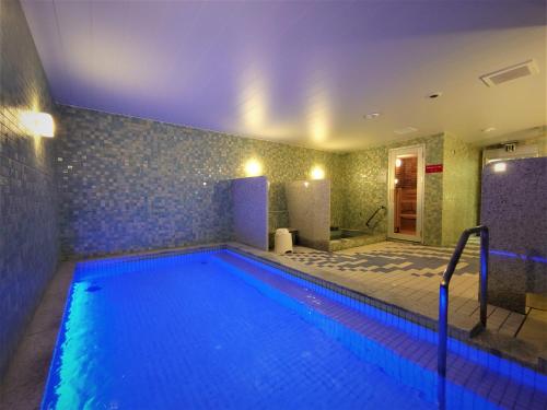 een groot zwembad met blauwe verlichting in een kamer bij Green Rich Hotel Miyazaki Tachibandori 2 (Artificial hot spring Futamata Yunohana) in Miyazaki
