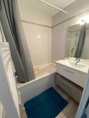 une salle de bain avec une baignoire, un lavabo et un miroir dans l'établissement Studio avec piscine à 300m de la plage Résidence Royal Park, à La Baule