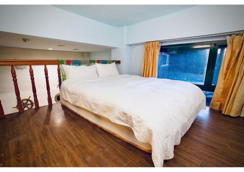 a large white bed in a room with a window at Old Street Seaview Homestay in Jiufen
