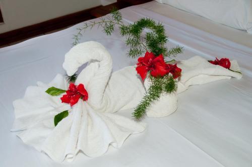 a towel swan with red flowers on a bed at Negril Palms in Negril