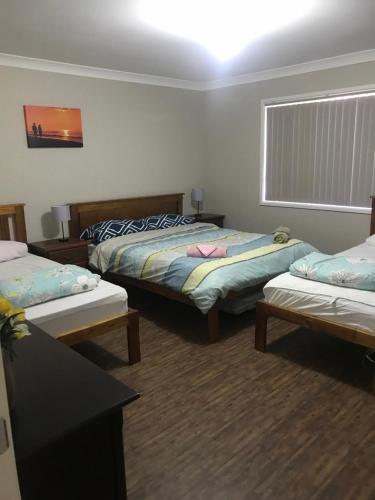um quarto com três camas e uma janela em Surf Mist em Nowra