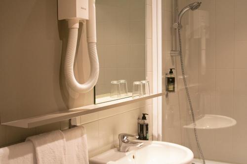 a bathroom with a sink and a shower with a mirror at Atlas Hotel Brussels in Brussels