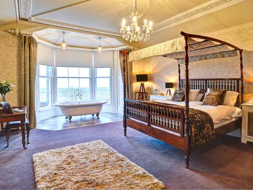 1 dormitorio con cama con dosel y bañera y 1 dormitorio con lámpara de araña. en Bay Villa, en Grange-over-Sands
