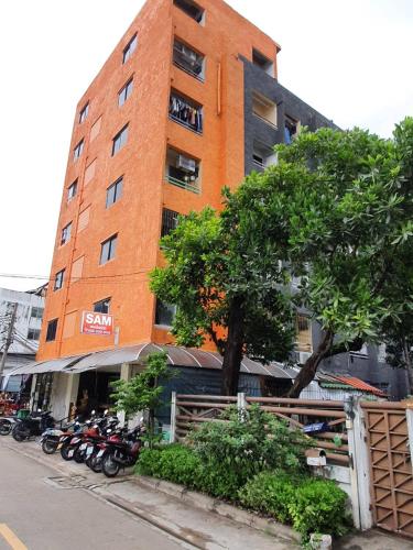 a tall orange building with motorcycles parked in front of it at SAM Apartment in Bangkok