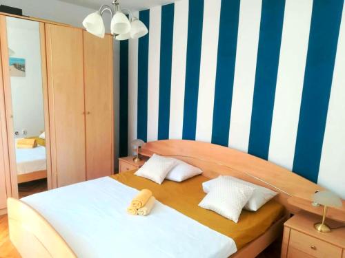 a bedroom with a bed with a blue and white striped wall at Apartman Viktorija in Bibinje