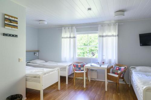 um quarto com 2 camas, uma secretária e uma janela em FolkiaCenter Gästhem - Vieraskoti - Guesthouse em Hanko