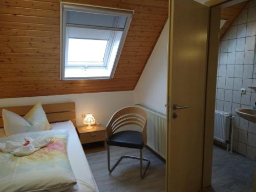 um quarto com uma cama, uma cadeira e uma janela em Pension "Der Sulzbachhof" em Lehrberg