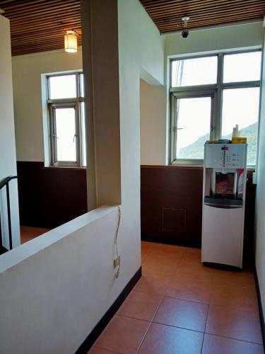 an empty room with a refrigerator and two windows at Old Street Seaview Homestay in Jiufen