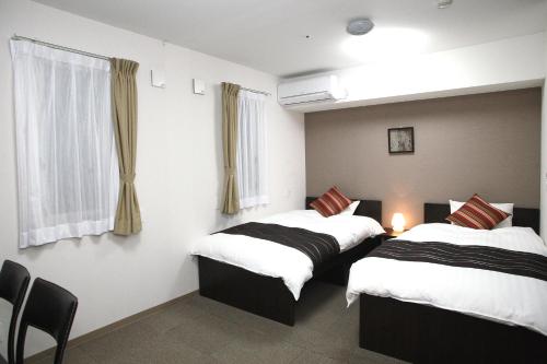 a room with two beds and a window at Value The Hotel Higashi Matsushima Yamoto in Higashimatsushima