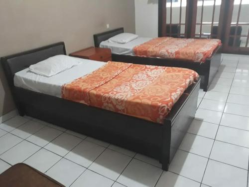 two beds are sitting in a room at Parama Hotel in Wonosobo