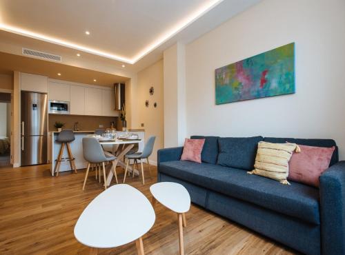 a living room with a blue couch and a table at San Martín Suites Apartments in Seville
