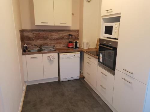une cuisine avec des armoires blanches et un four à plaques de cuisson dans l'établissement La Charmille, charmant 2P proche tram, à Strasbourg