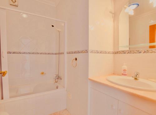 La salle de bains blanche est pourvue d'un lavabo et d'une douche. dans l'établissement Estrada de, Urbanizacao,edificio laranjal,apartment 18,vale carro, 8200-596, à Albufeira