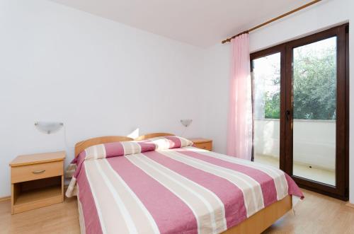 a white bedroom with a bed and a window at Apartment Marija in Poreč