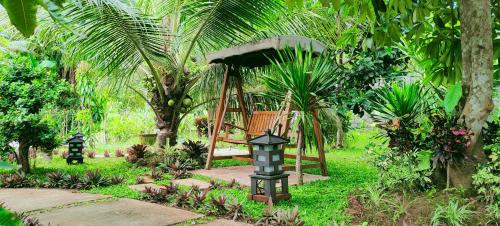 a gazebo in a garden with palm trees at Java Turtle Lodge Meru Betiri in Banyuwangi