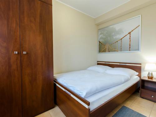 a bedroom with a bed and a wooden cabinet at VacationClub - Zielone Tarasy Apartament 51 in Kołobrzeg