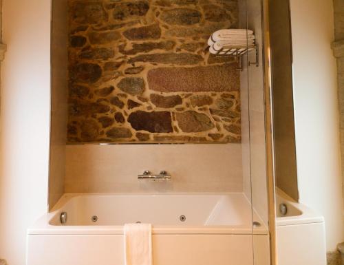 a bath tub in a bathroom with a stone wall at Hotel do Porto in Muros
