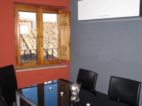 a dining room with a table with chairs and a window at Apartamento El Desván in Pedraza-Segovia