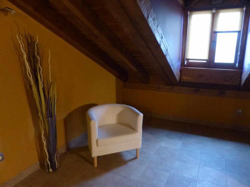 a white chair sitting in a room with a window at La casa de Don in Pedraza-Segovia
