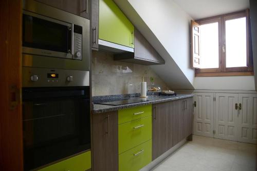 cocina con armarios verdes y microondas en Apartamento El Desván, en Pedraza-Segovia
