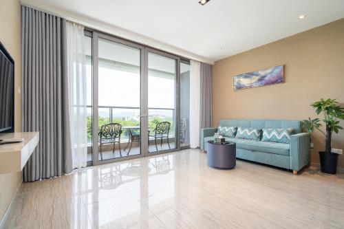 a living room with a blue couch and a balcony at Van-Pretty Residence Haitang Bay Sanya in Sanya