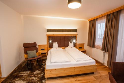 a bedroom with a large bed and a chair at Moseralm Dolomiti Spa Resort in Nova Levante