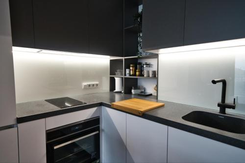 a kitchen with black and white cabinets and a sink at FITNESS room, Air conditioner, security & PARKING, fully equipped kitchen & washing machine, 4K OLED TV & HighSpeed WiFi, spacious balcony with gorgeous city view in CENTRAL location in Riga