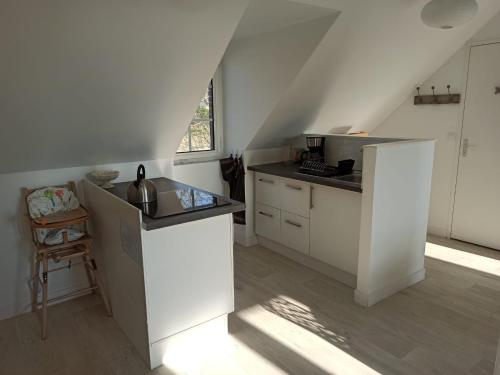 une cuisine avec des armoires blanches et un évier dans l'établissement Appartement des remparts, à Guérande