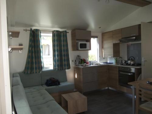 un salon avec un canapé et une cuisine dans l'établissement Assist' Mobil Home 289 - Mobil Home élégance 2 chambres 6 personnes, à Onzain