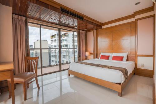 a bedroom with a bed and a desk and a window at Mike Beach Resort in Pattaya