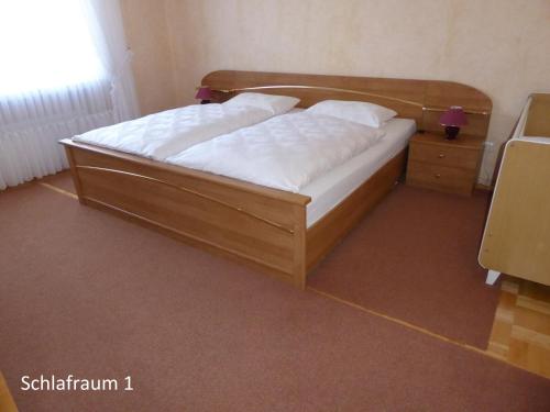 1 dormitorio con cama de madera con sábanas blancas en Ferienwohnung Waltraud, en Brilon