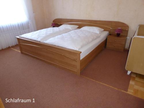 a bedroom with a wooden bed with white sheets at Ferienwohnung Waltraud in Brilon