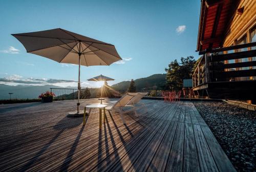 a table with an umbrella and chairs on a deck at Les Mazots du Clos in Villars-sur-Ollon