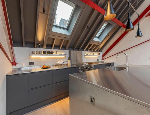 a kitchen with a stainless steel counter and windows at JOIVY Stylish 1-bed loft apartment near Battersea Park, South London in London