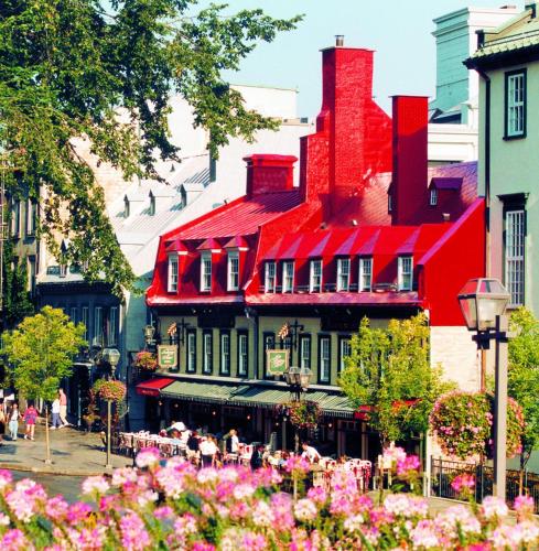 a red building with flowers in front of it at Auberge du Trésor in Quebec City