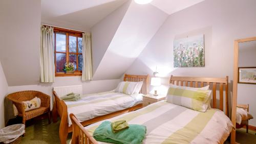 a twin bedroom with two beds and a chair at Osborne Steading in St Andrews