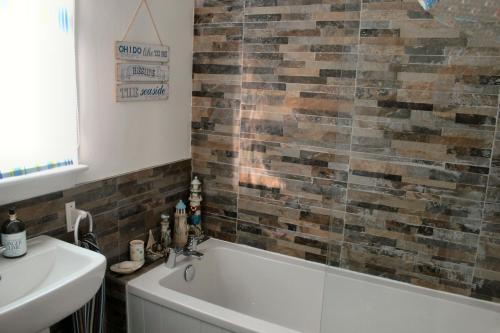 een badkamer met een ligbad en een wastafel bij Osborne Cottage in Southend