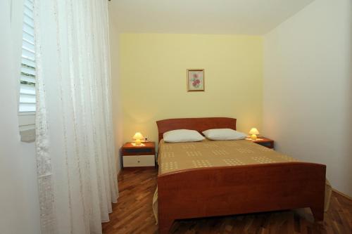 ein kleines Schlafzimmer mit einem Bett und zwei Nachttischen in der Unterkunft Apartmani Radan in Pag
