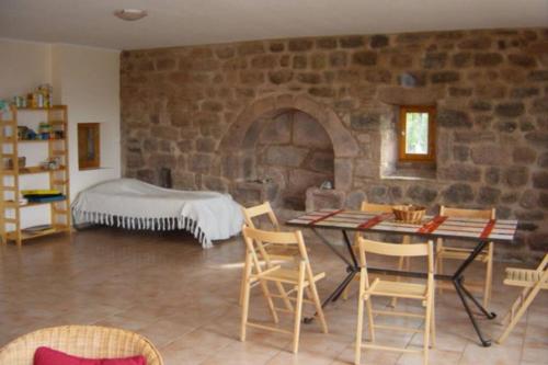 a room with a stone wall with a table and chairs at Belle et grande maison ardèchoise in Payzac