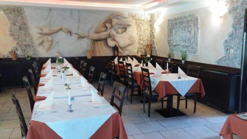 a row of tables in a restaurant with a painting on the wall at Hotel im Gässle in Süßen