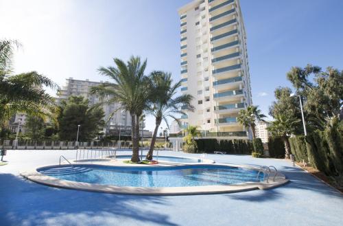 una piscina con un albero e un edificio di EDIFICIO LARIMAR a Calpe