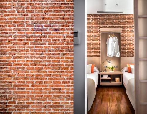 a room with a brick wall and two beds at Eric Vökel Boutique Apartments - Madrid Suites in Madrid