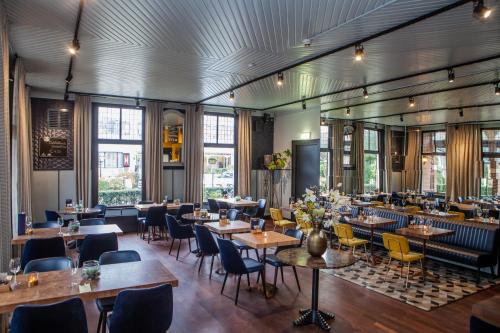 ein Restaurant mit Tischen, Stühlen und Fenstern in der Unterkunft Hotel van Renenpark in Bergen